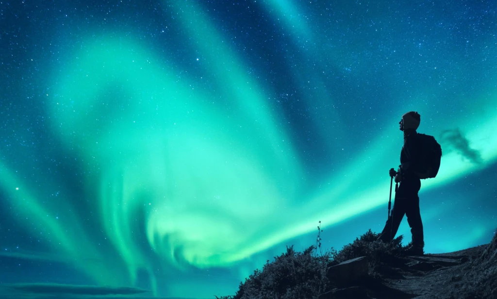 Aurora borealis and silhouette of a woman with backpack at night